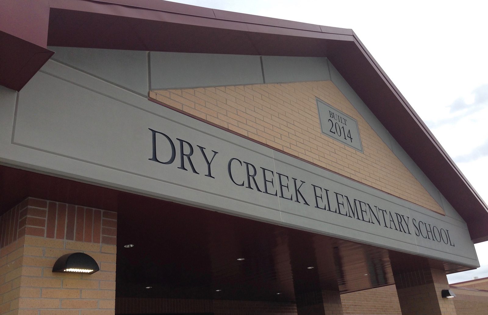 Monolithic Stone Finish with Embedded Custom Signage, Seamless Integration with Brick Veneer